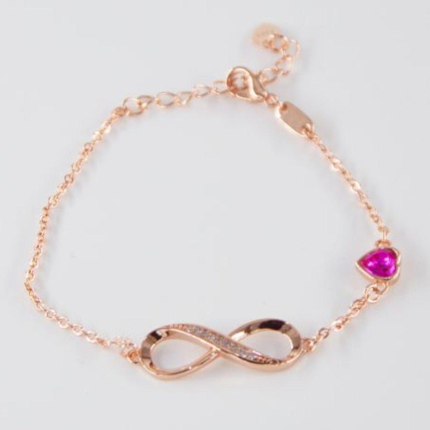 Armband mit Unendlichkeitszeichen-Anhänger in Roségold und einem roten Herzstein, stilvoll und elegant, perfekt als romantisches Geschenk